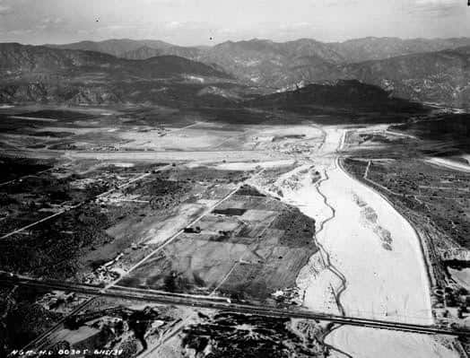 Aerial view of the Hansen Dam site in June 1939, showing the Tujunga Wash flood plain, early construction grading, and the San Gabriel Mountains in the distance.